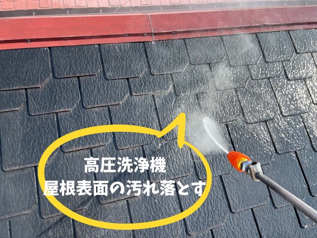 オレンジ色ノズルの高圧洗浄機でスレート屋根を洗浄している様子。水しぶきが均一に広がる。
