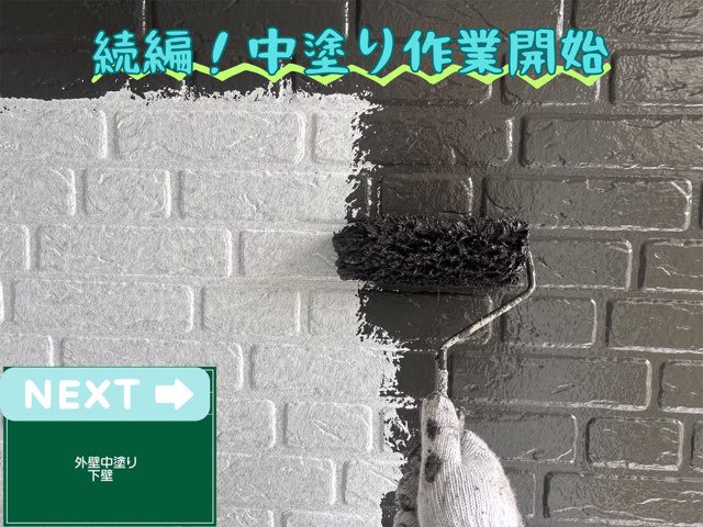 白い外壁にローラーで黒い塗料を塗っている中塗り作業の様子