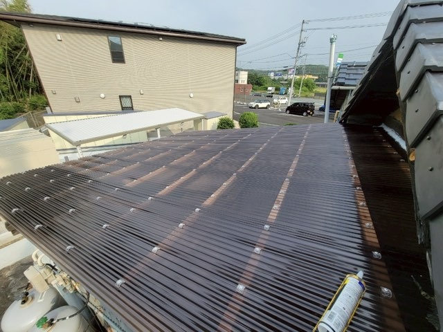 波型ポリカを張り終えた直後の屋根。ブラウン色のポリカが均一に敷かれ、光を反射している。