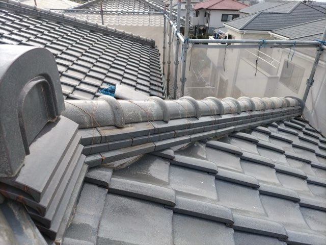 春日井市高森台にて棟の積み替え工事後の棟瓦。鬼瓦やのし瓦が整然と並び、銅線で丁寧に緊結されている。漆喰も美しく施工され、仕上がりが均一で安心感がある屋根の状態。