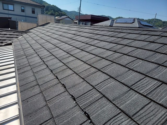岐阜市加野にて葺き替え工事後の黒いTルーフヴェルウッドが施工された屋根全体の写真　細かな石粒仕上げと横方向の模様が特徴です