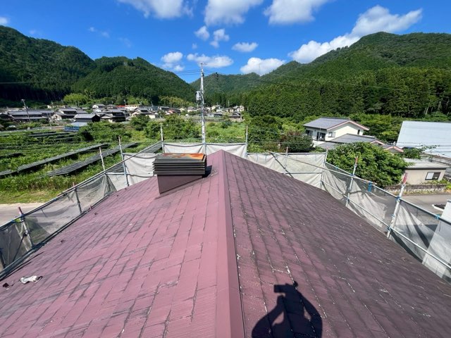 施工前のスレート屋根。紫色の屋根表面に色あせや汚れが見られ、中央には換気塔が設置されている。