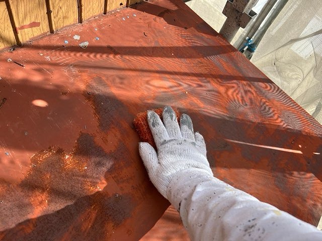 多治見市平井町の庇塗装前、手作業でケレンを行いサビや古い塗膜を落としている様子。鉄部の赤サビが浮き出て劣化が進んでいる状態。