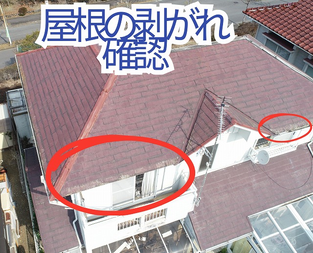 屋根の端部分でスレート材の剥がれが見られる様子