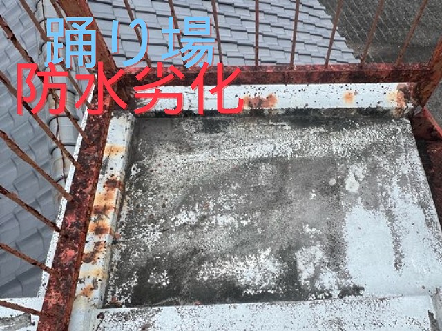 踊り場床面の防水が劣化し、防水層が剥がれて黒ずんだ状態