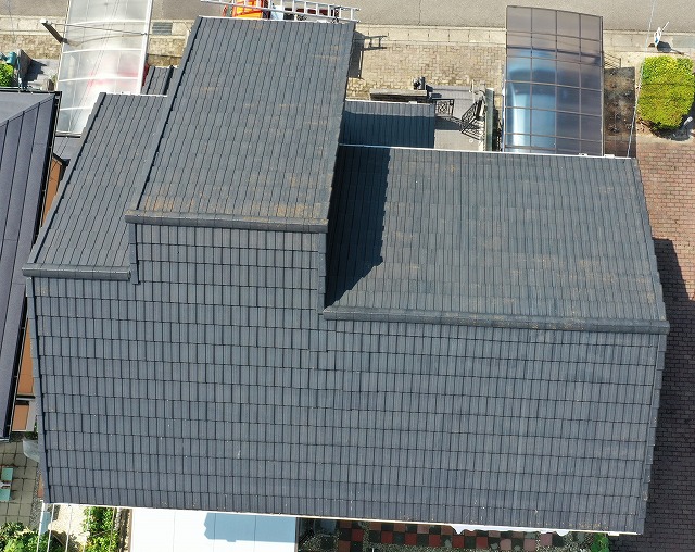 施工前の屋根を真上から撮影した写真。瓦の色あせや汚れが見られ、複数箇所で劣化が進行している状態。瓦のズレ・段差による影もあり、全体的に経年劣化が感じられる屋根の様子。