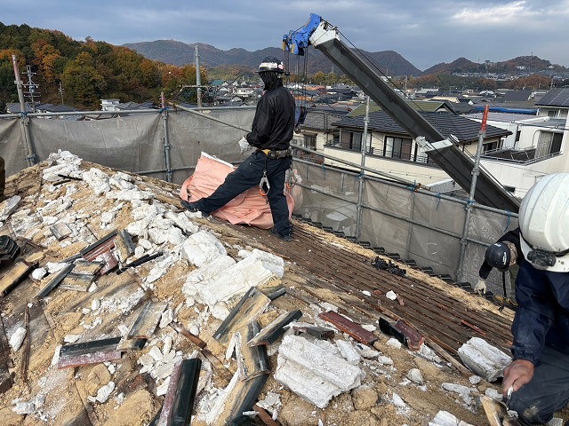 瓦をめくっている　下地が弱く踏み抜かないよう気をつけている