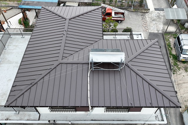 瀬戸市坂上町にて立平板金で屋根の葺き替え工事と雨樋交換工事を行った完工後のドローン写真。落ち着いた色合いの金属屋根がきれいに仕上がり、棟や屋根面も整っている様子が確認できる。