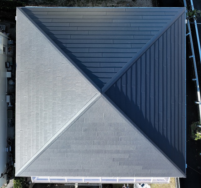 多治見市脇之島町にて屋根カバー工事と外壁塗装、雨樋交換工事が完了した住宅のドローン撮影写真。屋根全体がきれいに仕上がっている様子。