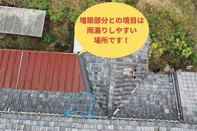 赤い板金屋根と古い瓦屋根が接する境目部分を上空から確認した様子