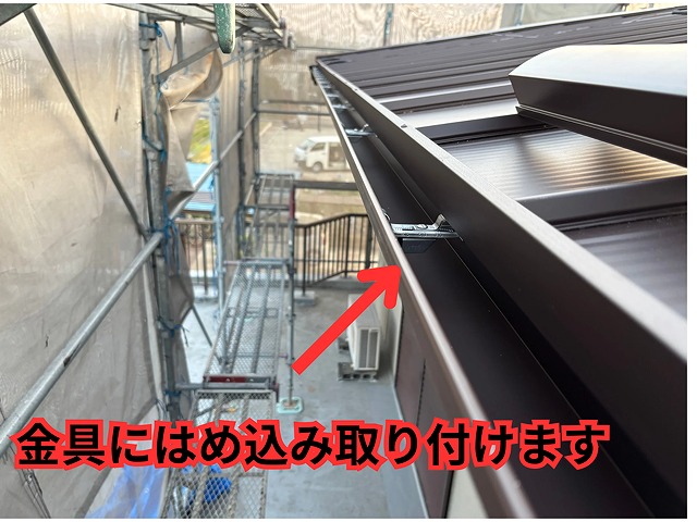 新しい雨樋を金具にはめ込んで取り付けている様子
