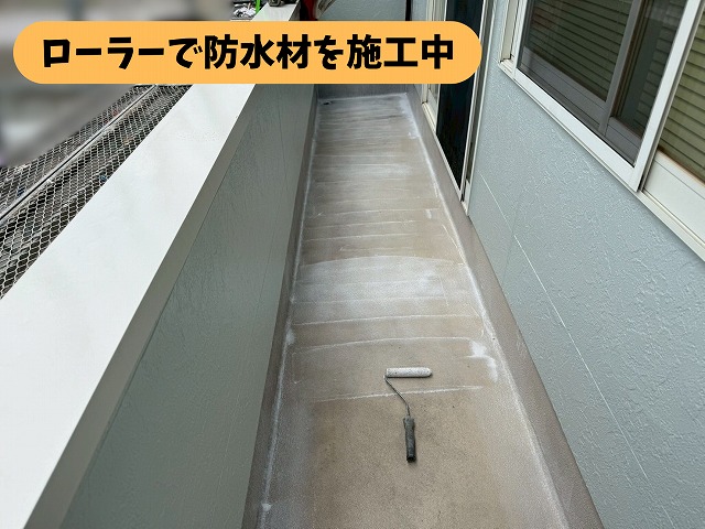 瑞浪市明世町のベランダ床にローラーで防水材を施工している様子