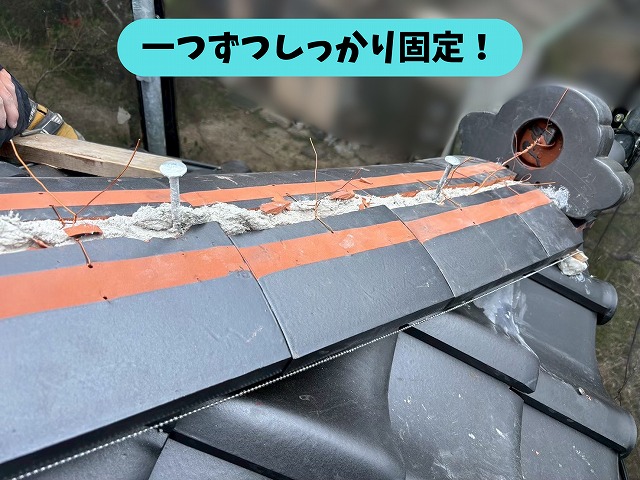 瓦屋根の棟瓦を工具でしっかり固定している施工の様子