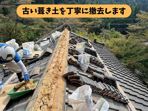 瓦屋根の棟部分で職人が古い葺き土を撤去する作業風景
