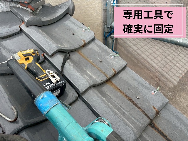 専用工具を使用して軒瓦をビス固定する作業の様子。瓦を傷めないよう慎重に施工しています