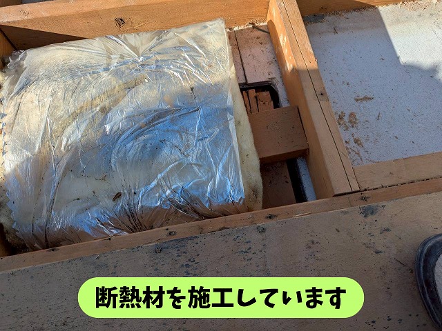 屋根の下地部分に断熱材を入れて施工している様子